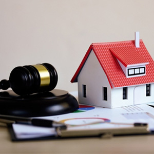 Judge's gavel and house model on financial charts for estate planning asset distribution.